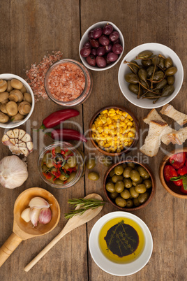 Olives with spice and corns with oil in bowl on table