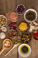 Olives with spice and corns with oil in bowl on table