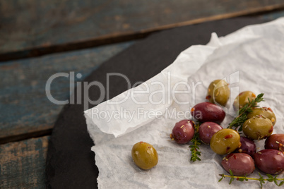 Overhead view of green and brown olives on wax paper