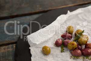 Overhead view of green and brown olives on wax paper