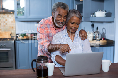 Man gesturing while woman using laptop