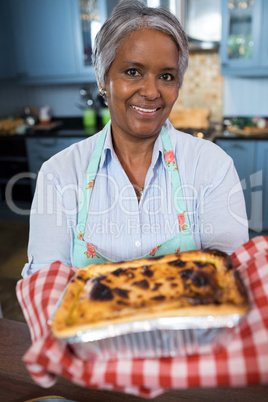 Close up portrait of senior woman showing baked food
