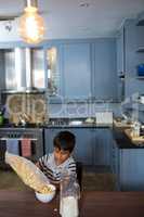 High angle view of boy pouring cereals in bowl