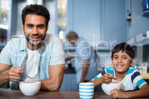 Portrait of father and son having breakfast with man in background