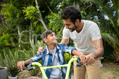 Father and son standing with bicycle while looking at each other