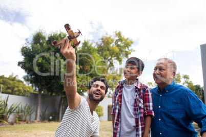 Boy with grandfather looking at man holding toy airplane