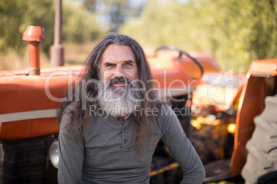 Portrait of happy man sitting against tractor in olive farm