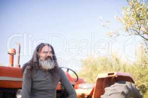 Thoughtful man sitting against tractor in olive farm