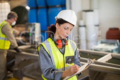 Female technician writing on clipboard