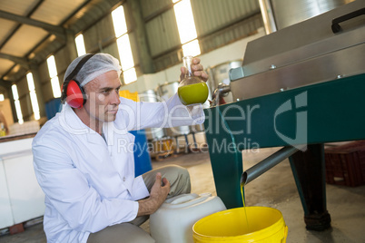 Technician examining olive oil produced from machine