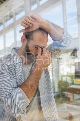 Tensed designer leaning seen through glass