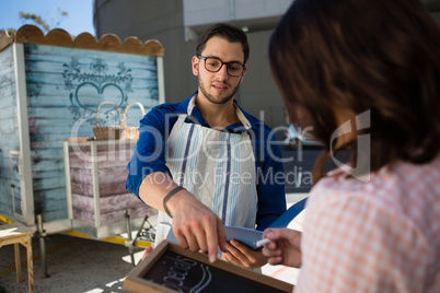 Man talking to coworker writing menu by food truck