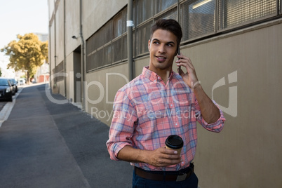 Man talking on phone while walking by wall