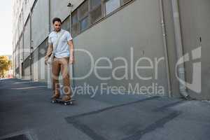 Young man skating on footpath by building