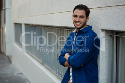 Confident man with arms crossed leaning on wall