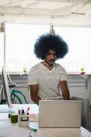 Man with curly hair using laptop in office
