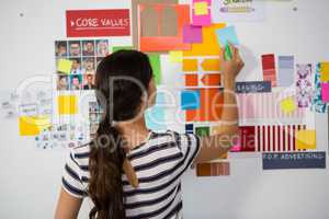 Rear view of woman writing on sticky note in office