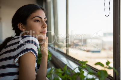 Thoughtful woman looking through window at office