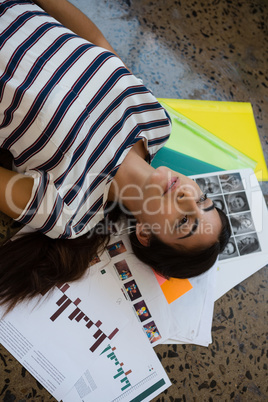 High angle view of thoughtful woman lying on documents at office