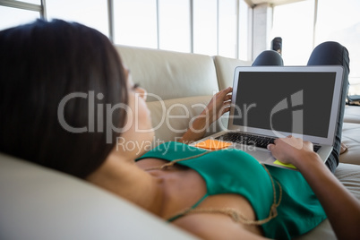Young woman using laptop on sofa at office