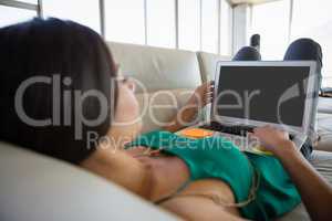 Young woman using laptop on sofa at office