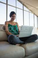 Woman using laptop while relaxing on sofa at office