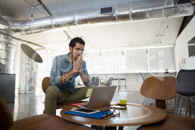 Tired man sitting by table in office