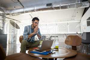 Tired man sitting by table in office