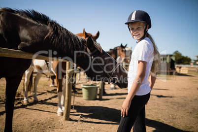 Smiling girl standing near the horse in ranch