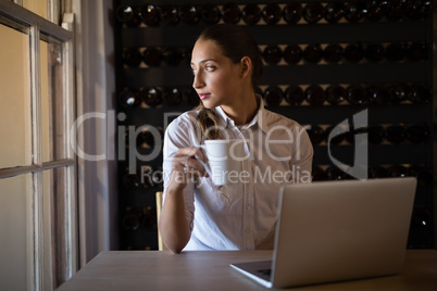 Woman looking through window while having coffee in cafÃ?Â©