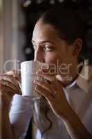 Woman looking through window while having coffee in cafÃ?Â©