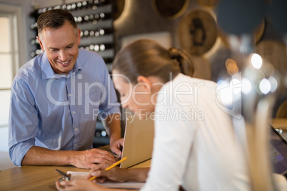 Manager and bartender discussing over clipboard in bar