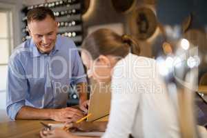 Manager and bartender discussing over clipboard in bar
