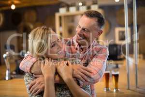 Man embracing woman from back in bar