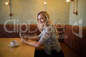 Smiling beautiful woman using mobile phone at table