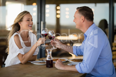 Happy couple toasting wine glass while having meal