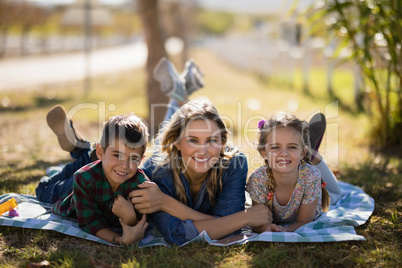 Happy mother and kids lying on blanket in park