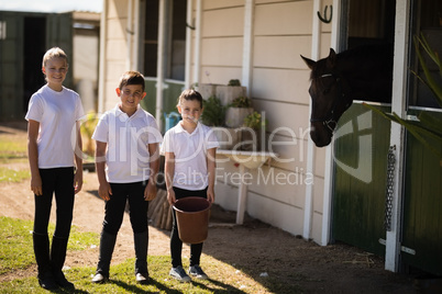 Kids standing with a bucket to feed the horse