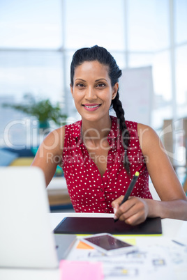 Female graphic designer using digital tablet at desk