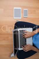 Female executive using laptop while sitting on wooden floor