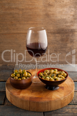 High angle view of green olives served in bowl by wineglass