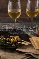 Green olives served in plate by crackers with white wine