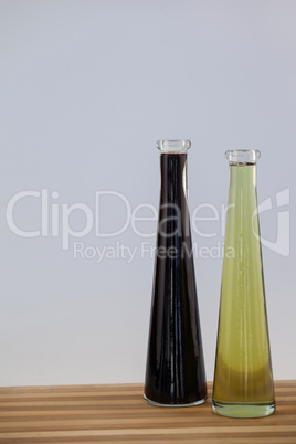 Black and green olive oil in bottle on wooden table