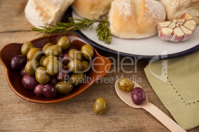 High angle view of olives in plate by bread