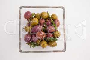 Overhead view of olives with herbs served in glass bowl