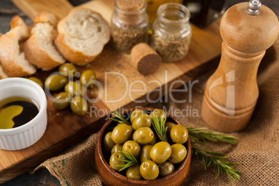 High angle view of olives by pepper shaker and cutting board