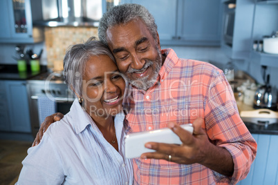 Smiling couple taking selfie at home