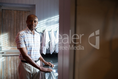 Portrait of senior man standing by window