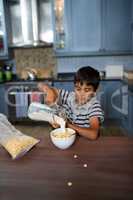 Boy pouring milk in cereals