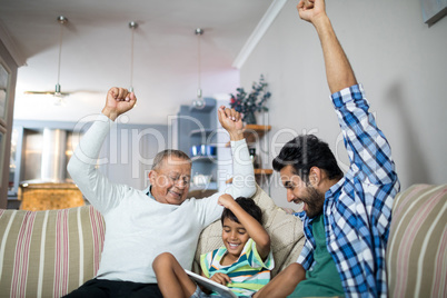 Cheerful family with arms raised siting on sofa